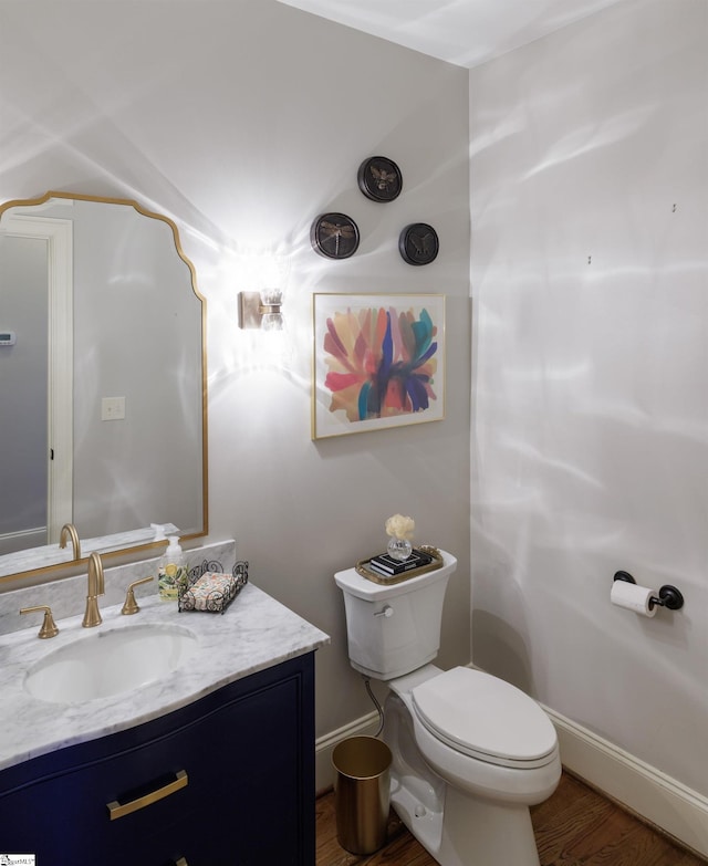 bathroom with baseboards, vanity, toilet, and wood finished floors