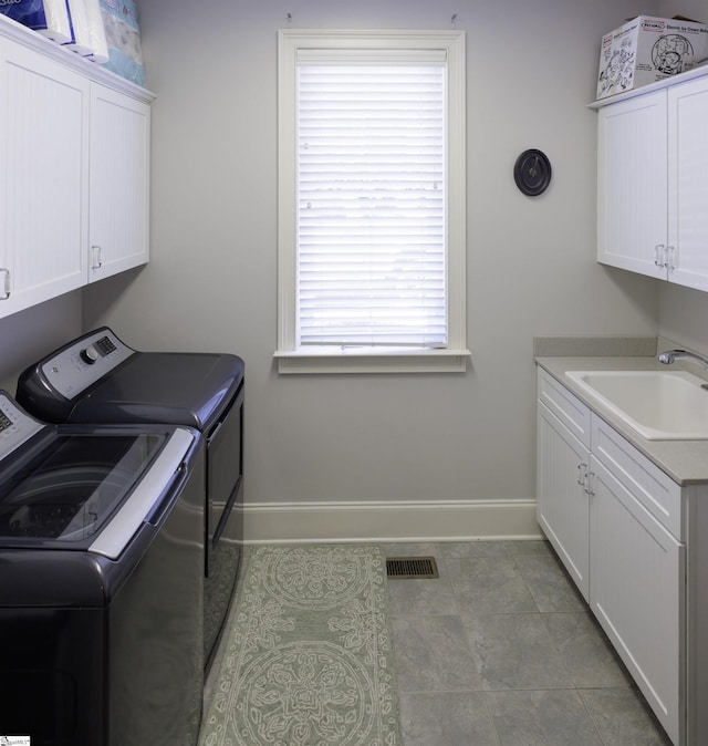 laundry area featuring cabinet space, baseboards, visible vents, separate washer and dryer, and a sink