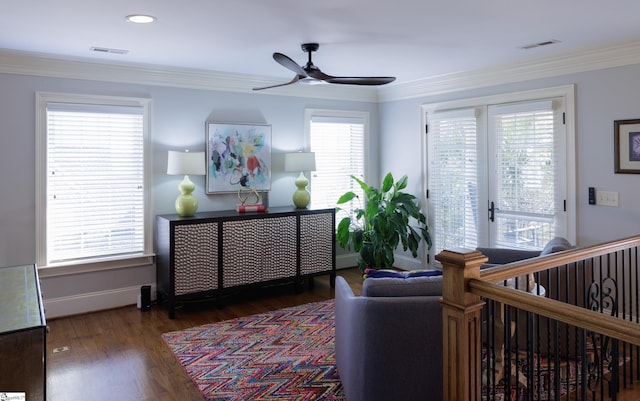 living area with dark wood-style floors, a healthy amount of sunlight, visible vents, and crown molding