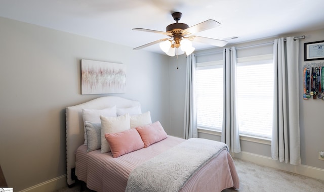 bedroom with light colored carpet, ceiling fan, visible vents, and baseboards