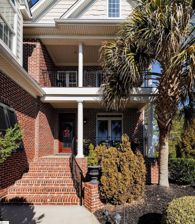 property entrance with covered porch and brick siding