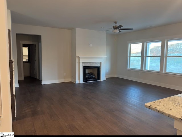 unfurnished living room with a tile fireplace, dark wood finished floors, and baseboards