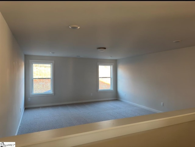 unfurnished room featuring light carpet and baseboards