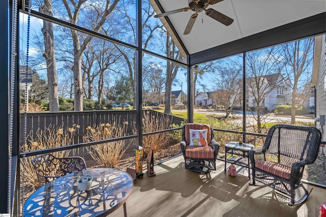 sunroom featuring vaulted ceiling, ceiling fan, and a residential view