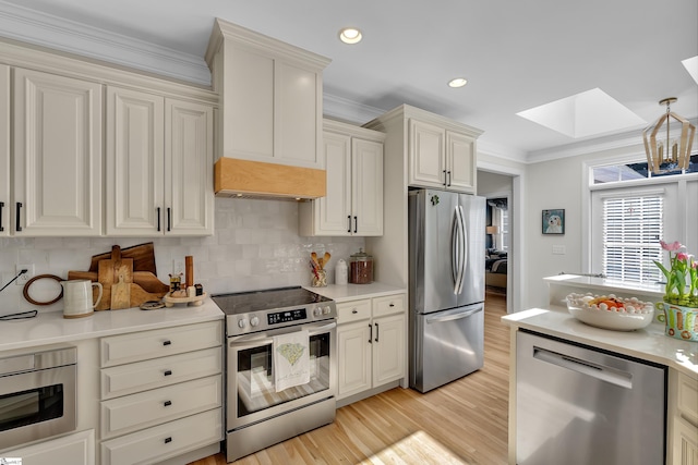 kitchen featuring a skylight, stainless steel appliances, light countertops, ornamental molding, and premium range hood