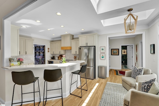 kitchen with cream cabinets, open floor plan, light countertops, and freestanding refrigerator