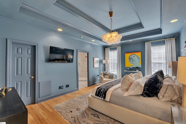 bedroom with a tray ceiling, multiple windows, wood finished floors, and visible vents