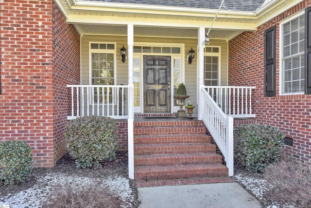 property entrance with roof with shingles, brick siding, crawl space, and a porch