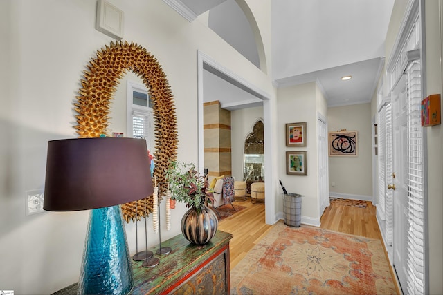 hall featuring baseboards, light wood finished floors, and crown molding