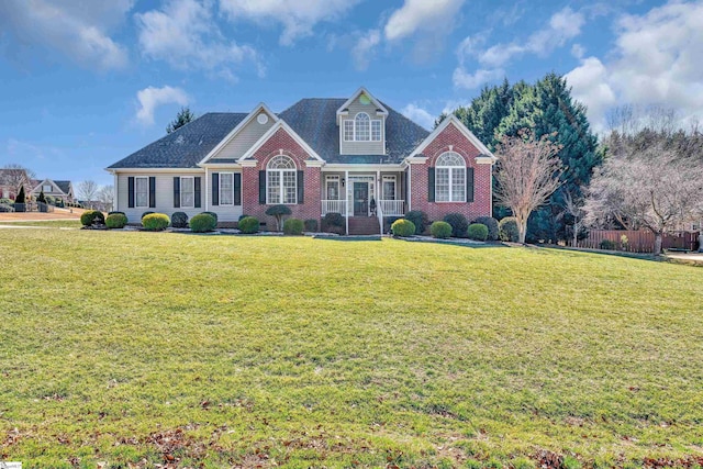 view of front of house featuring brick siding, a front lawn, and fence