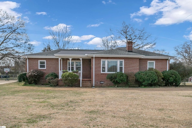 view of front of home featuring brick siding, roof with shingles, a chimney, a front yard, and crawl space