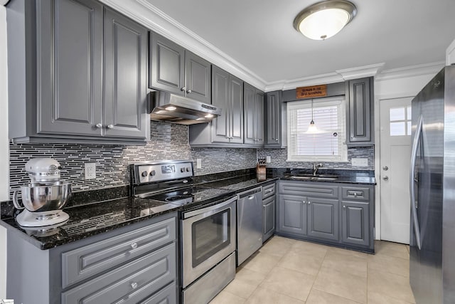 kitchen with under cabinet range hood, stainless steel appliances, a sink, gray cabinets, and pendant lighting