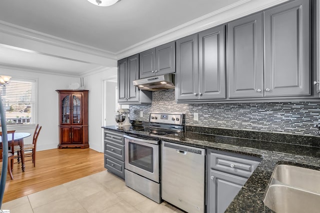 kitchen featuring ornamental molding, appliances with stainless steel finishes, dark stone countertops, and under cabinet range hood