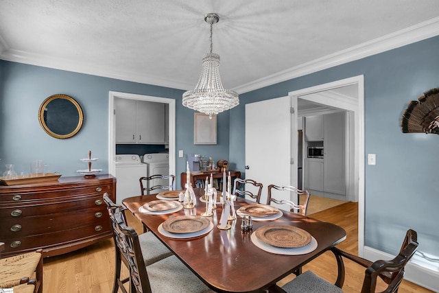 dining space featuring baseboards, washer and clothes dryer, crown molding, light wood-style floors, and a chandelier