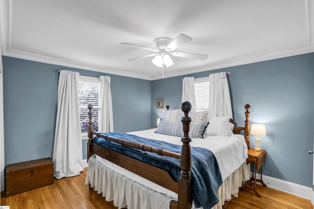 bedroom with baseboards, light wood-type flooring, a ceiling fan, and crown molding