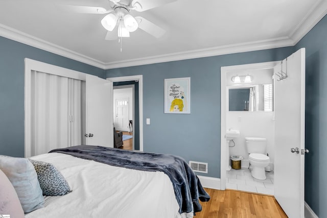 bedroom featuring visible vents, crown molding, baseboards, and wood finished floors