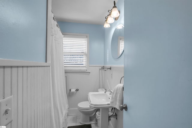 bathroom with a wainscoted wall and toilet