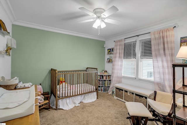 bedroom featuring a nursery area, carpet floors, ornamental molding, and ceiling fan