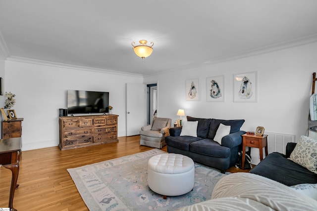 living room with baseboards, wood finished floors, visible vents, and crown molding