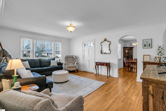 living room featuring light wood-style floors, baseboards, arched walkways, and crown molding