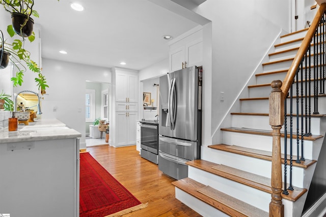 kitchen with appliances with stainless steel finishes, recessed lighting, white cabinetry, and light wood-style flooring