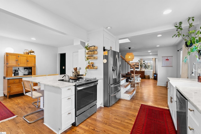 kitchen with appliances with stainless steel finishes, white cabinetry, and light stone countertops