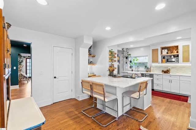 kitchen featuring white cabinets, a breakfast bar area, a center island, stainless steel appliances, and open shelves