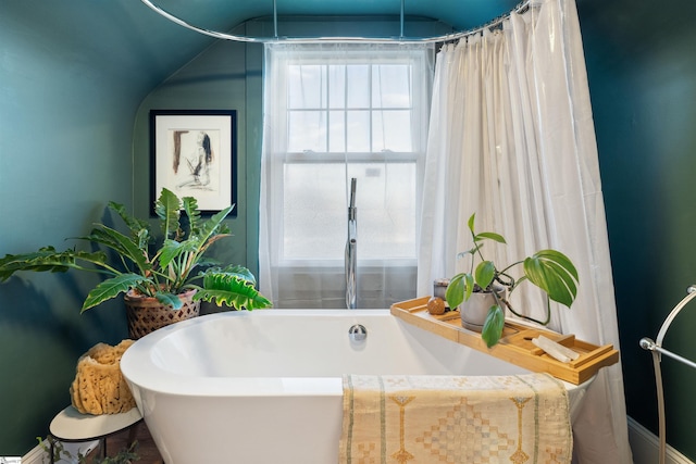 bathroom featuring lofted ceiling and a freestanding bath