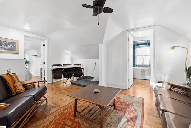 living area featuring a ceiling fan, baseboards, vaulted ceiling, and light wood finished floors