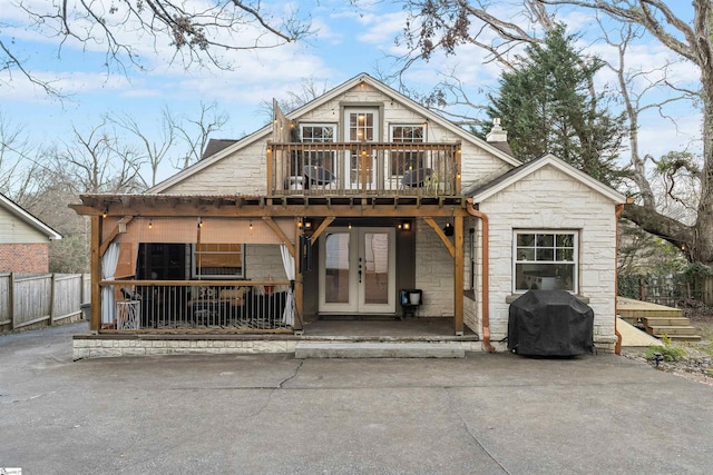 chalet / cabin featuring stone siding, french doors, fence, and a balcony