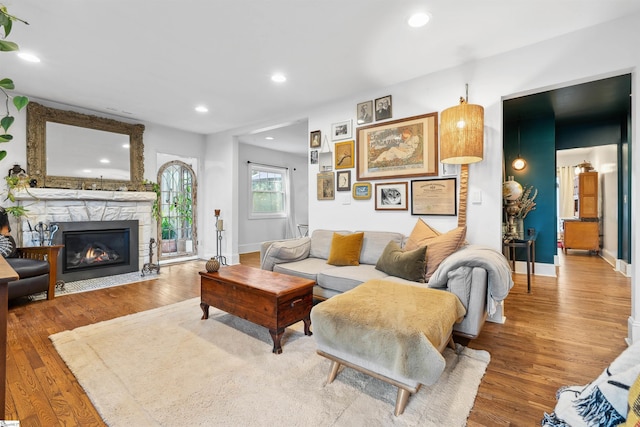 living area with recessed lighting, wood finished floors, and a stone fireplace