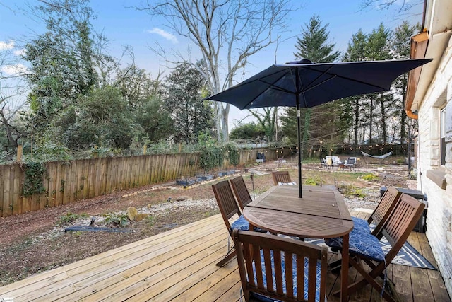 wooden deck with a fenced backyard and outdoor dining area