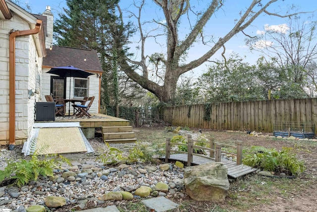 view of yard with a fenced backyard, outdoor dining area, and a wooden deck