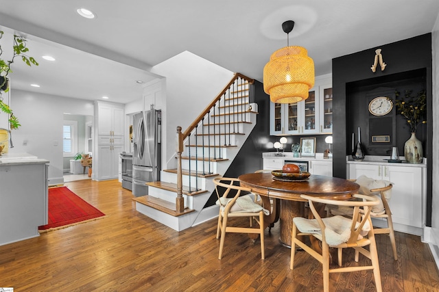 dining space featuring recessed lighting, wood finished floors, and stairs