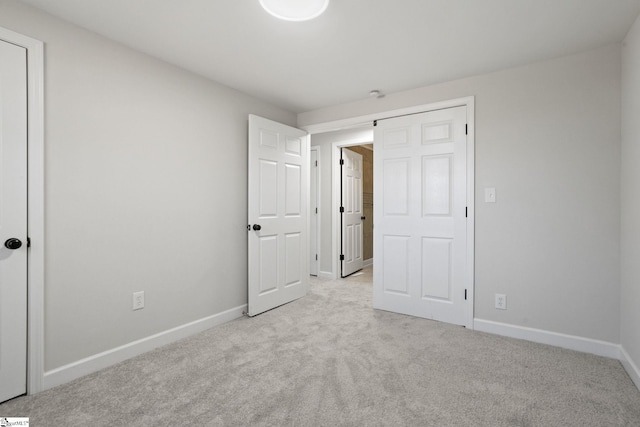 unfurnished bedroom featuring light carpet and baseboards