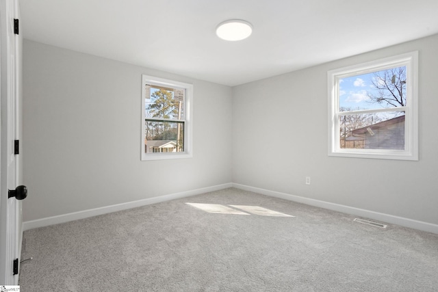 spare room featuring light carpet, visible vents, and baseboards