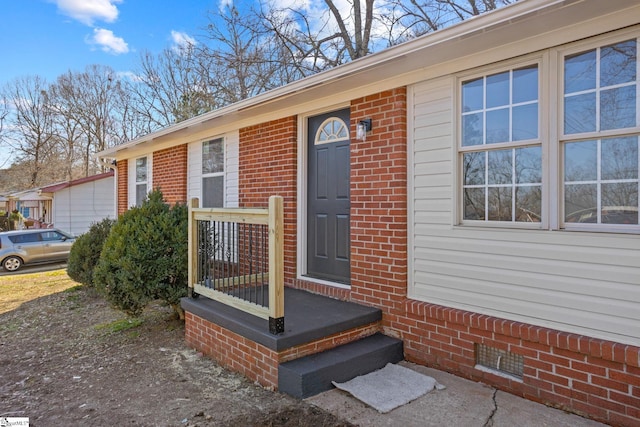 view of exterior entry with brick siding and crawl space