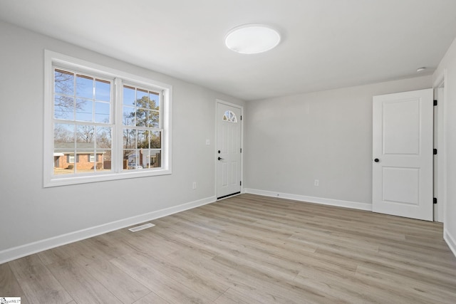 spare room featuring light wood-style flooring, visible vents, and baseboards