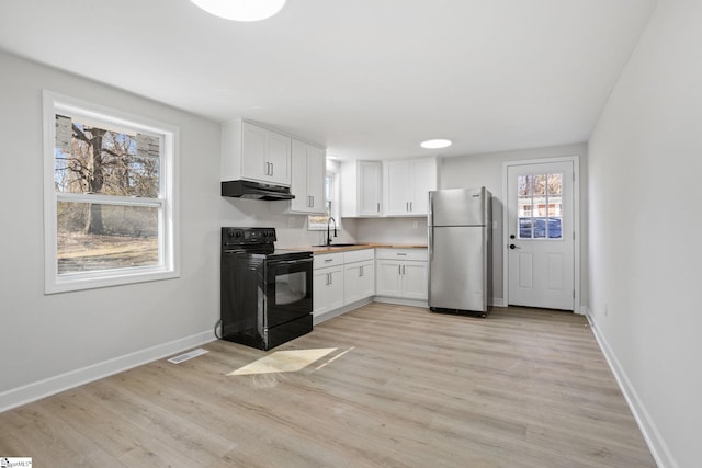 kitchen featuring freestanding refrigerator, black / electric stove, under cabinet range hood, white cabinetry, and a sink