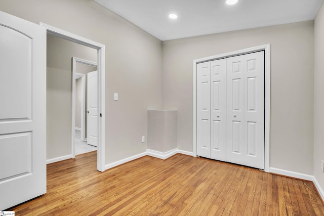 unfurnished bedroom featuring a closet, light wood-style flooring, and baseboards