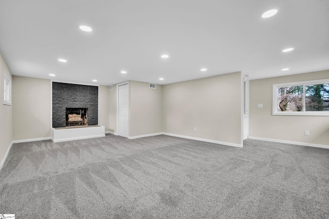 unfurnished living room featuring a large fireplace, recessed lighting, visible vents, and light colored carpet