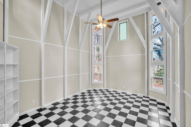 empty room with plenty of natural light, a towering ceiling, baseboards, and ceiling fan