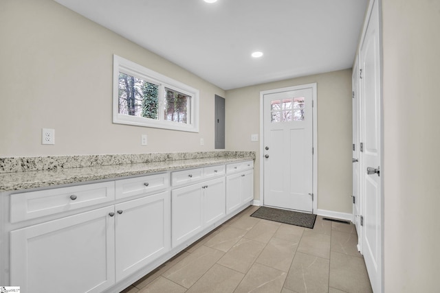 kitchen with a healthy amount of sunlight, baseboards, light stone counters, and white cabinets