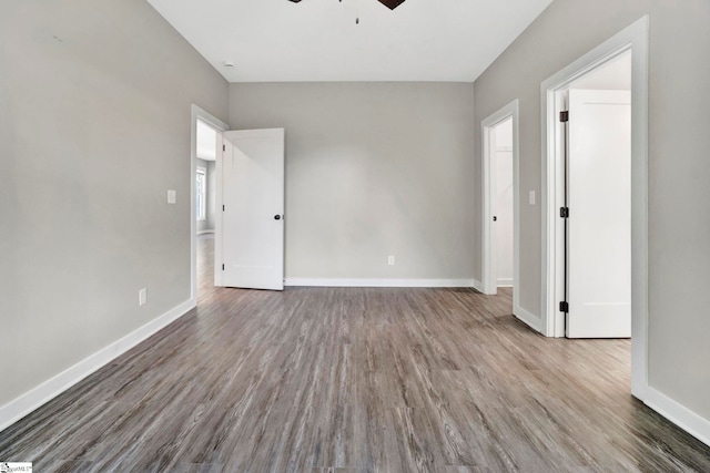 unfurnished room featuring a ceiling fan, baseboards, and wood finished floors