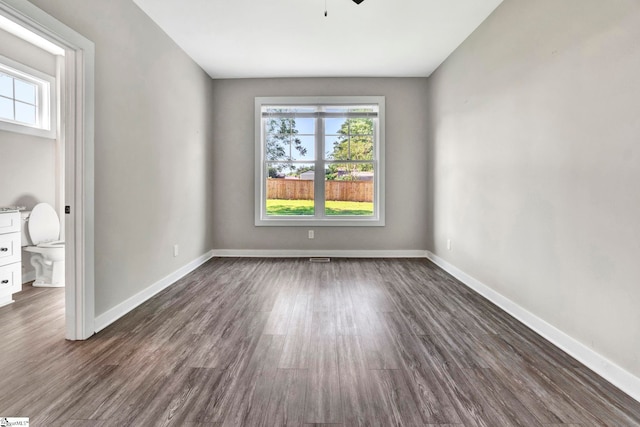 spare room featuring a ceiling fan, dark wood-style flooring, and baseboards