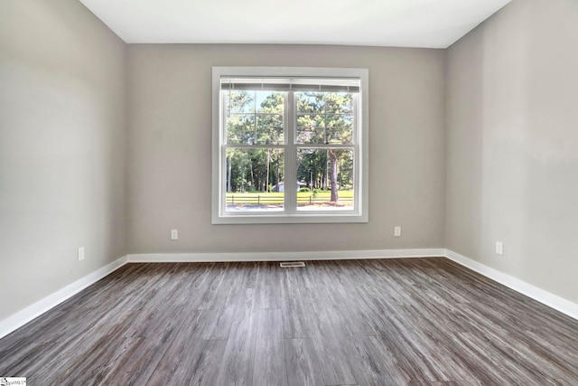 empty room with visible vents, baseboards, and dark wood-type flooring