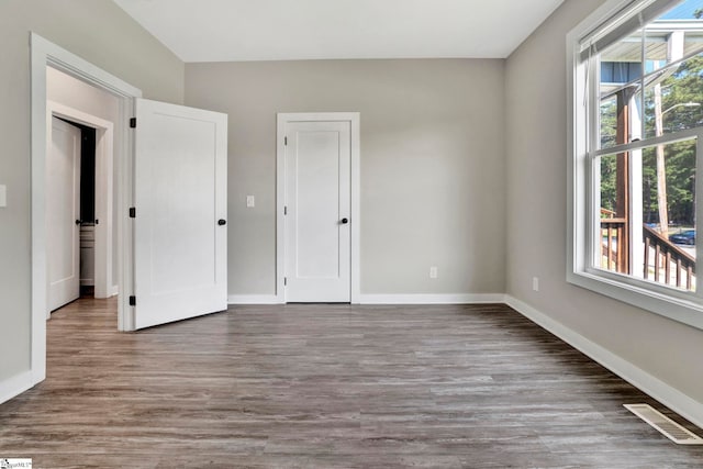 unfurnished bedroom featuring dark wood-type flooring, visible vents, and baseboards