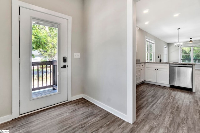 doorway to outside featuring baseboards, wood finished floors, a chandelier, a sink, and recessed lighting