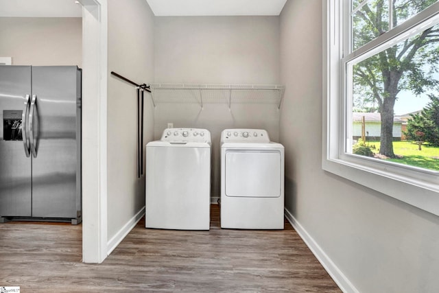 washroom featuring light wood-style floors, washing machine and dryer, laundry area, and baseboards