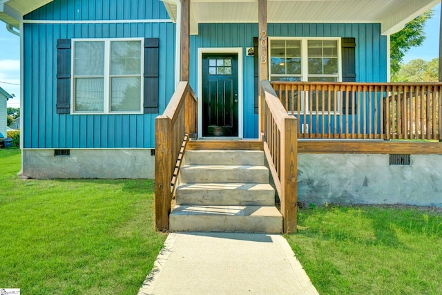 view of exterior entry with crawl space, board and batten siding, and a lawn